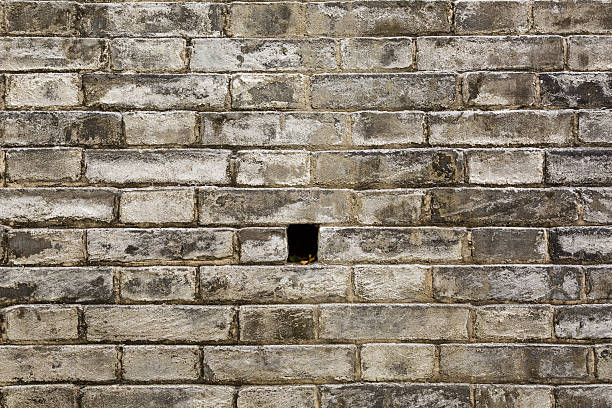 Texture of old stone block retaining wall with weep hole for draining