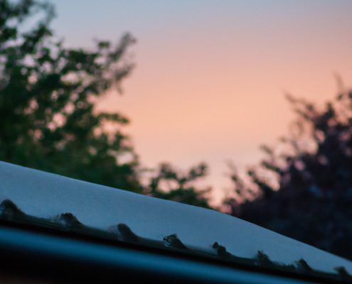 a house roof in the foreground with a beautiful summers day sunset in the background